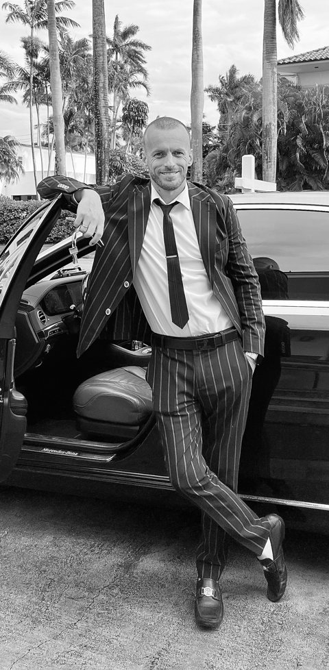 Roman Lytvyn in a pinstripe suit beside an open car